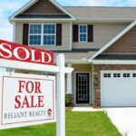 A real estate sign that reads sold, in front of a newer home. 