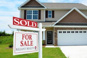 A real estate sign that reads sold, in front of a newer home.